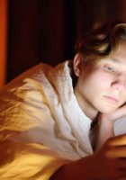 Adolescdente mirando móvil en la cama